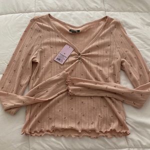 A pastel pink shirt with a flower print. Has never been worn